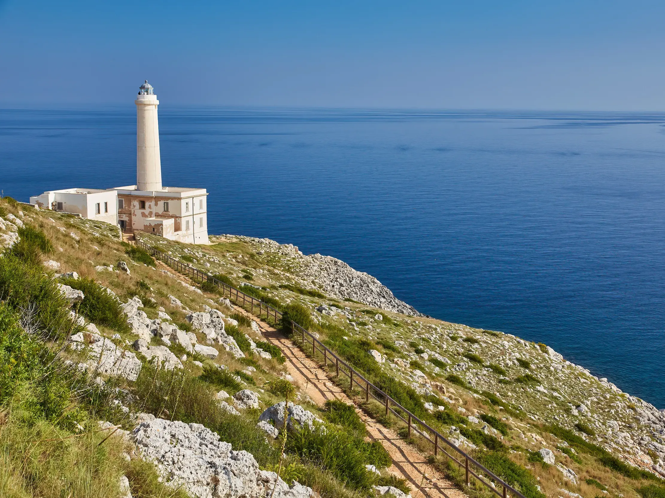 Wanderweg entlang der Klippen zum Leuchtturm am Kap von Otranto mit weitem Blick über die blaue Adria in Apulien.