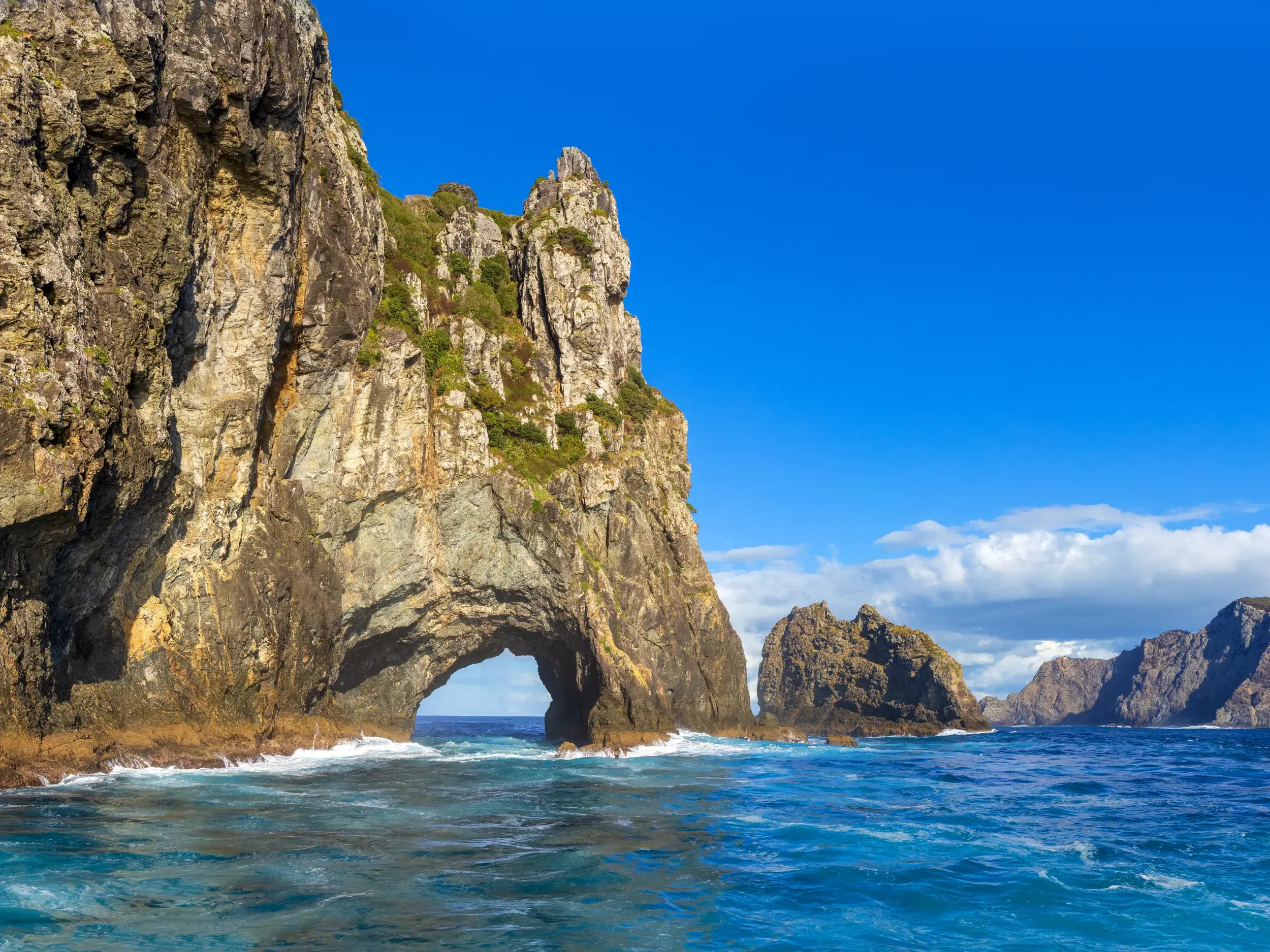 Das berühmte Felsentor Hole in the Rock in der Bay of Islands bei einer Bootsfahrt während einer Studiosus-Reise in Neuseeland.
