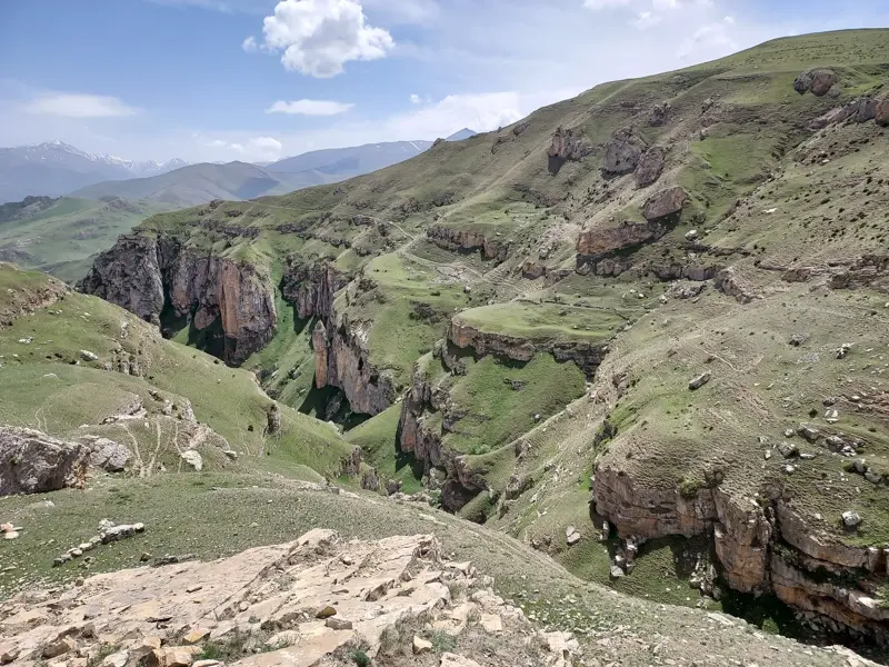 Panoramablick in eine tiefe, grüne Schlucht mit steilen Felswänden beim Trekking im Großen Kaukasus in Aserbaidschan.