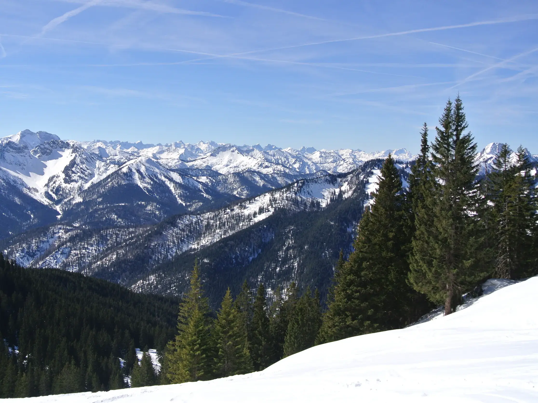 Weite Aussicht beim Schneeschuhwandern auf die verschneite Gebirgskette des Karwendel an einem sonnigen Wintertag.