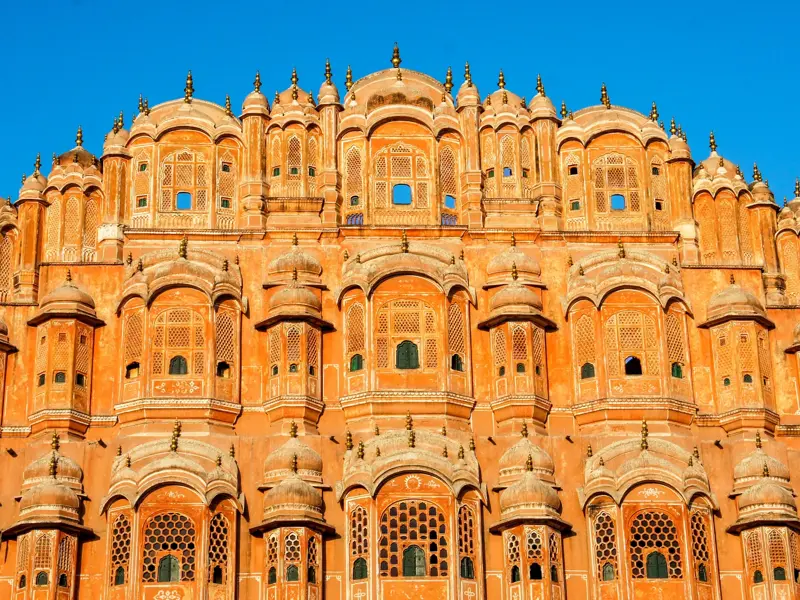 Die kunstvolle, rosafarbene Fassade des Hawa Mahal, auch Palast der Winde, in Jaipur bei strahlend blauem Himmel.