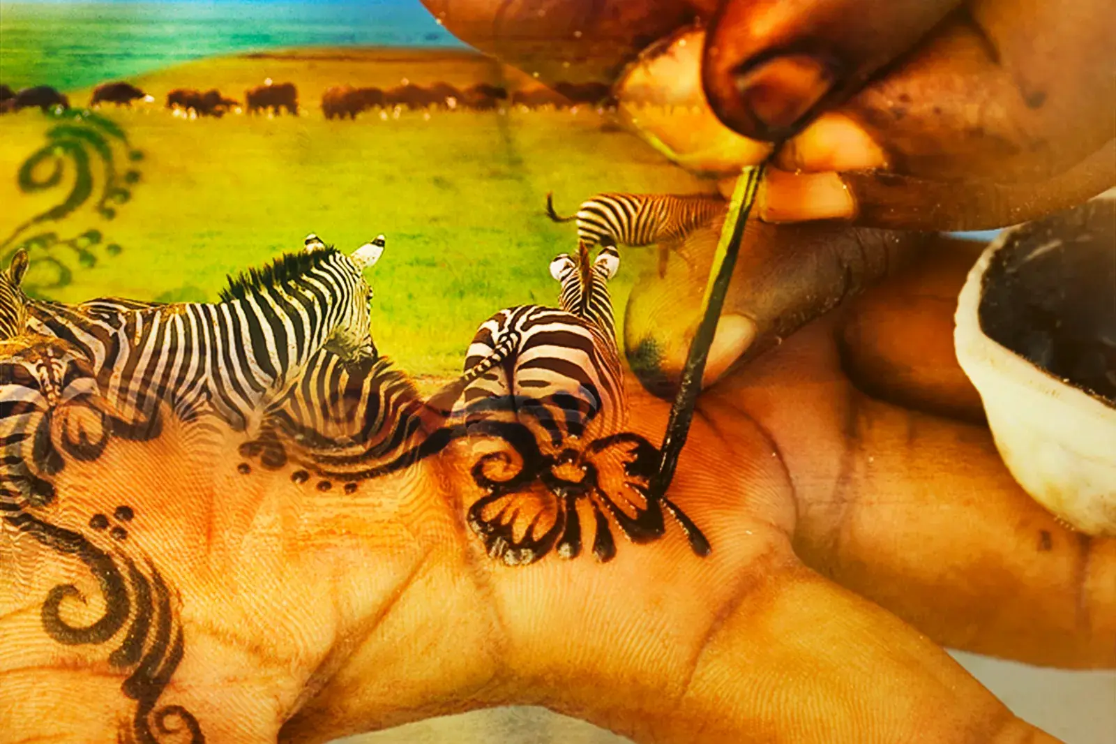 Eine Hand wird kunstvoll mit Zebras und Ornamenten bemalt, eine kreative Darstellung der Safari-Erlebnisse in Tansania.