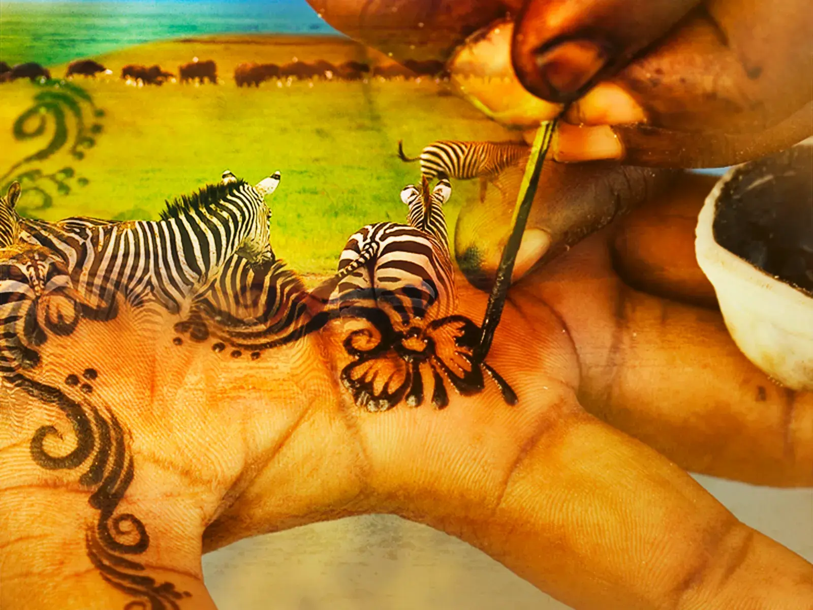 Eine Hand wird kunstvoll mit Zebras und Ornamenten bemalt, eine kreative Darstellung der Safari-Erlebnisse in Tansania.