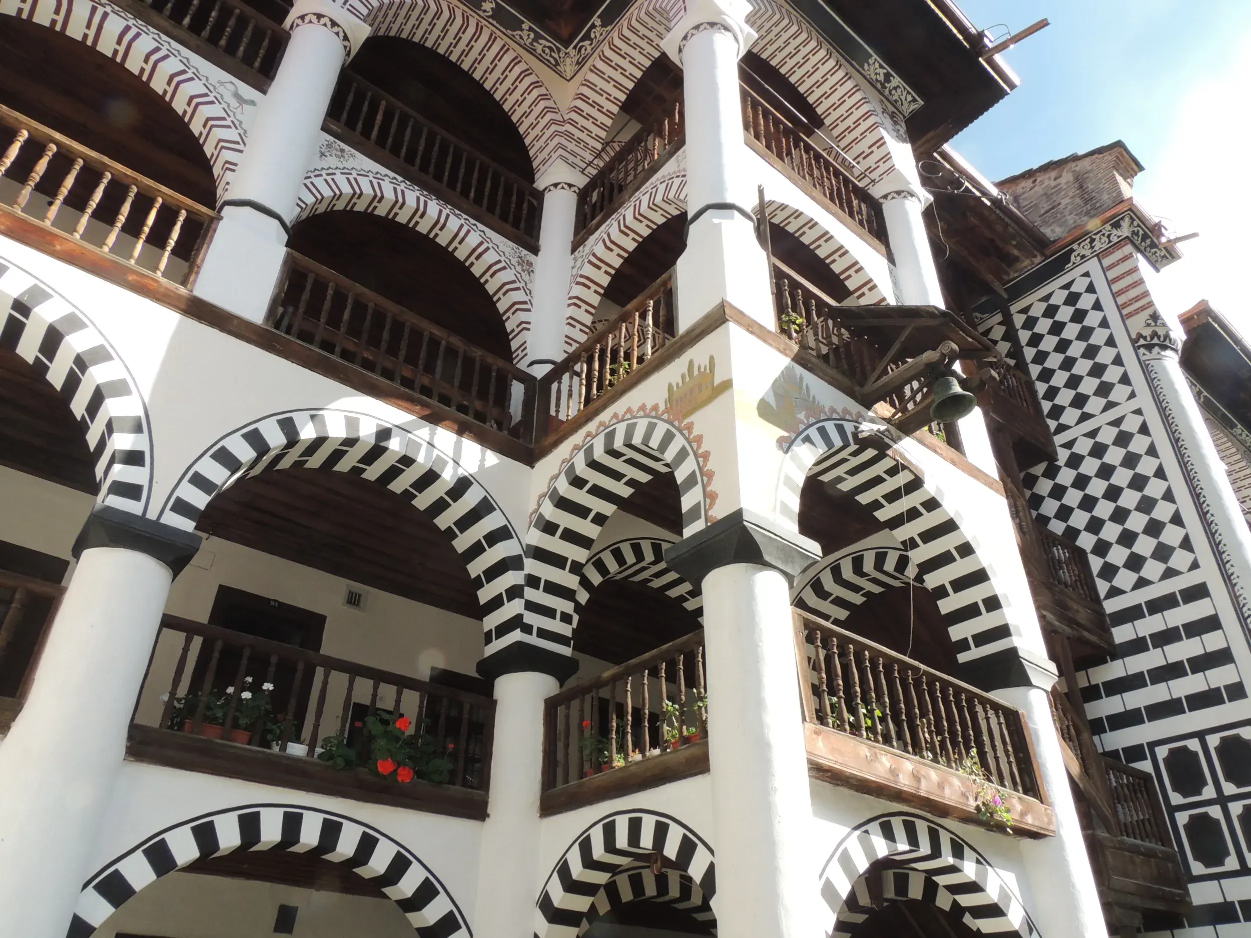 Einblick in den Innenhof des Rila-Klosters im Rila-Gebirge mit den typischen schwarz-weiß bemalten Arkadenbögen und Holzbalkonen.