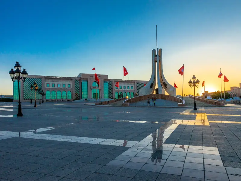 Ein futuristisches Monument und ein modernes Regierungsgebäude in Taschkent im warmen Licht des Sonnenuntergangs.