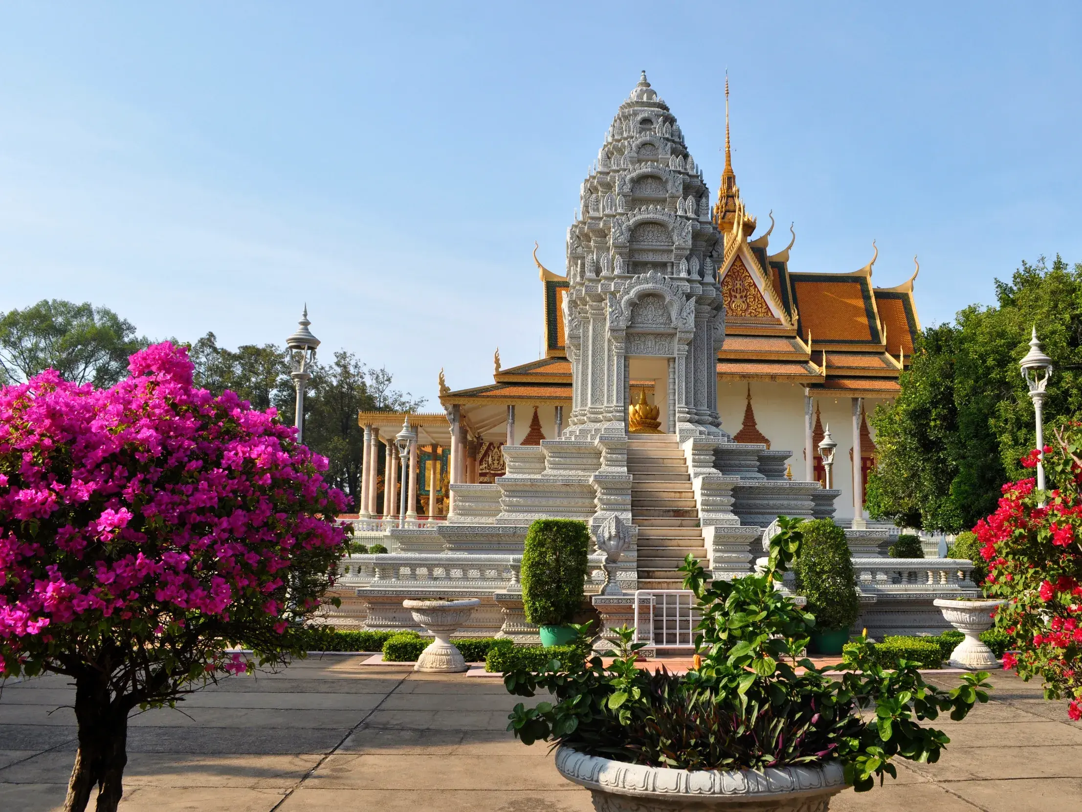 Der Stupa von König Norodom vor der Silberpagode im Königspalast von Phnom Penh, eingerahmt von pinken und roten Blüten.