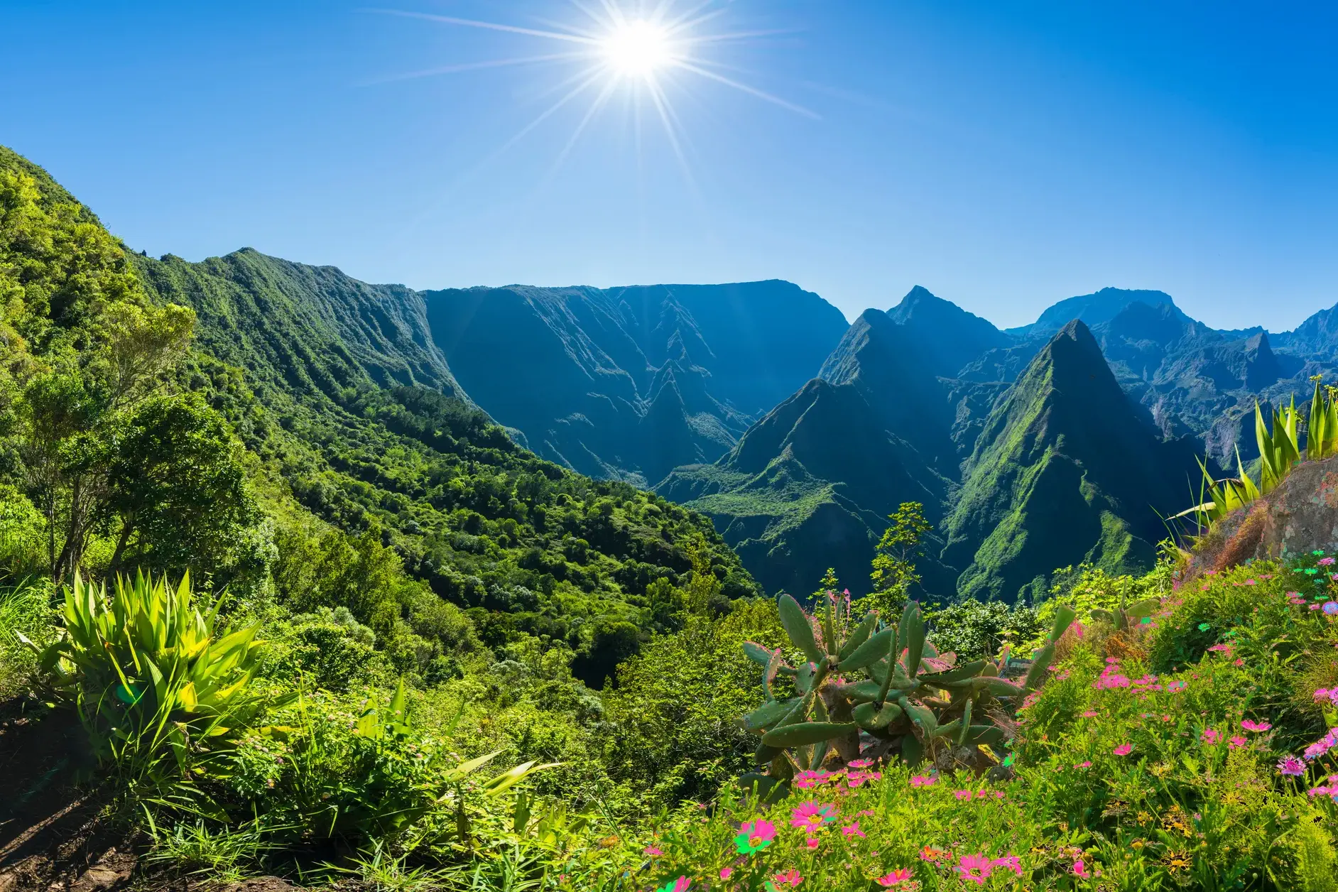 Strahlende Sonne über der üppig grünen Vulkanlandschaft des Mafate-Talkessels auf La Réunion bei einer Trekking-Tour.