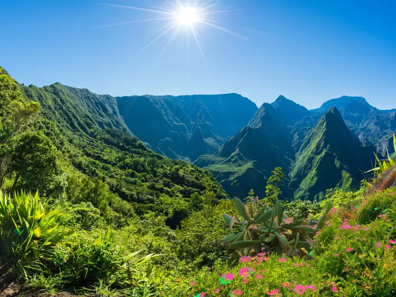 Strahlende Sonne über der üppig grünen Vulkanlandschaft des Mafate-Talkessels auf La Réunion bei einer Trekking-Tour.