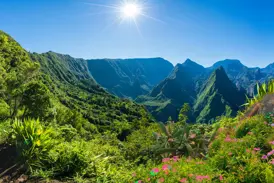 Strahlende Sonne über der üppig grünen Vulkanlandschaft des Mafate-Talkessels auf La Réunion bei einer Trekking-Tour.