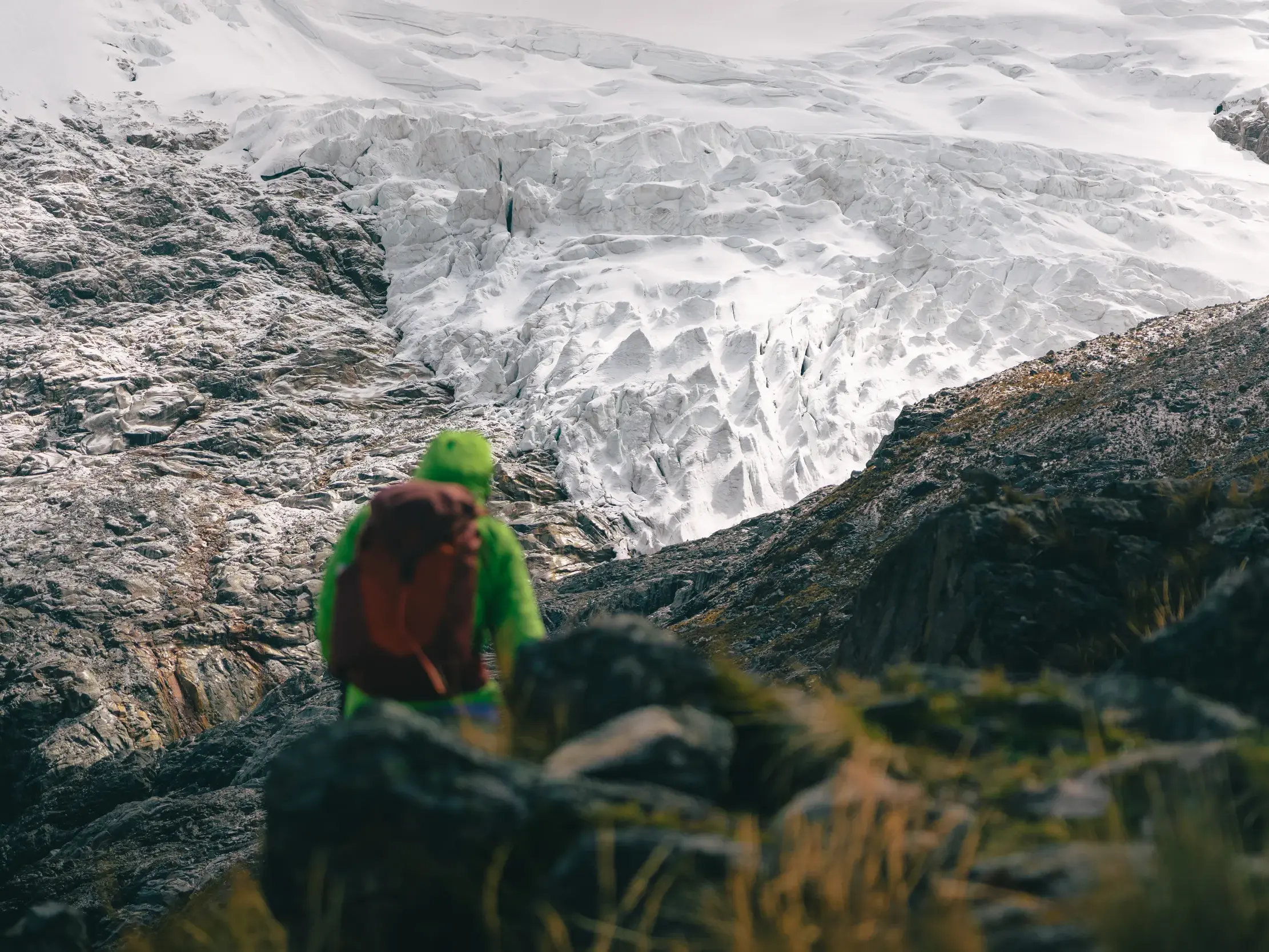 Ein Wanderer blickt bei einer Trekking-Tour in der Cordillera Blanca in den peruanischen Anden auf eine gewaltige Gletscherfront.