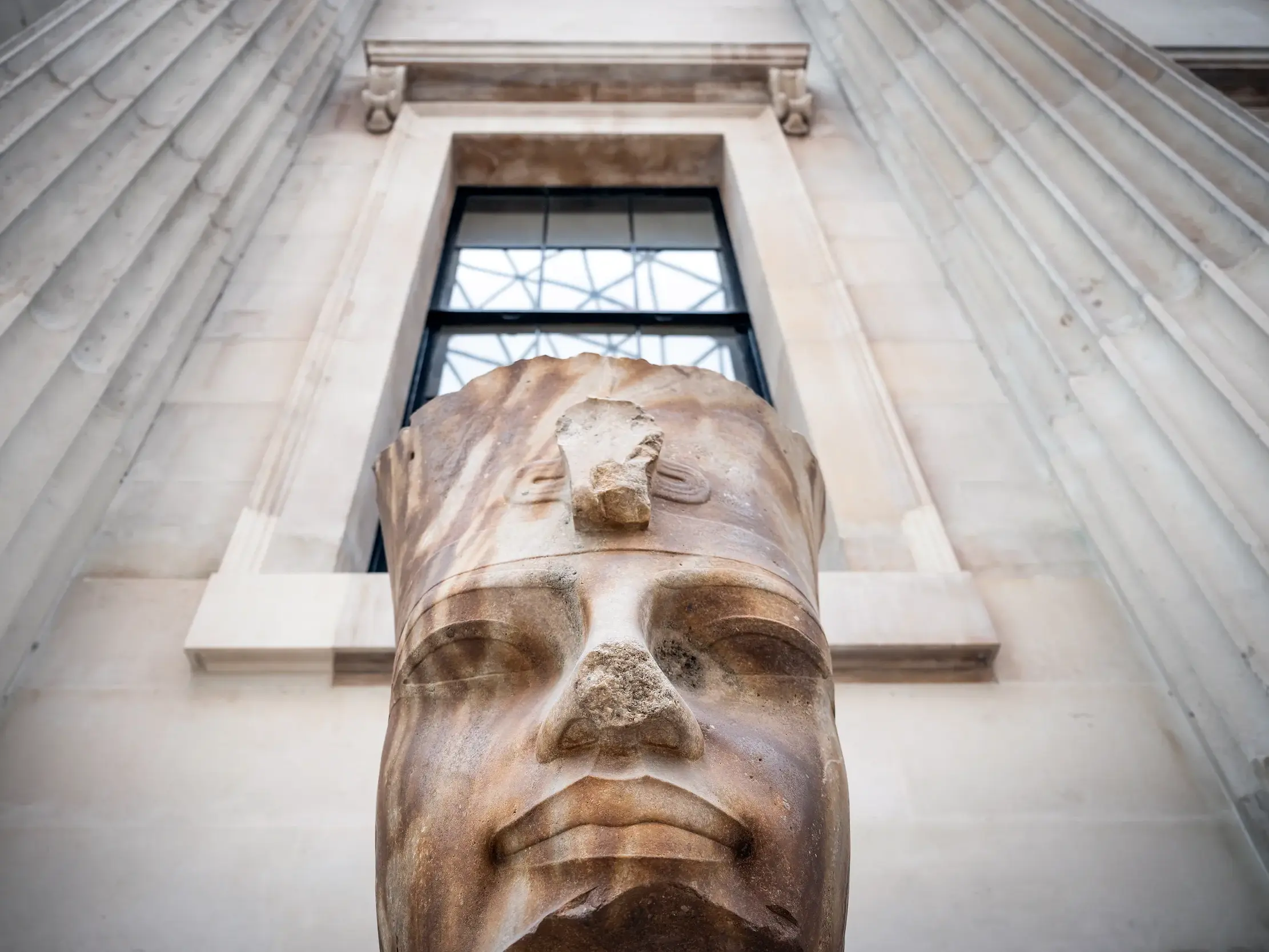 Kolossale Büste eines ägyptischen Pharaos in der Skulpturengalerie des British Museum in London vor hohen Steinsäulen.