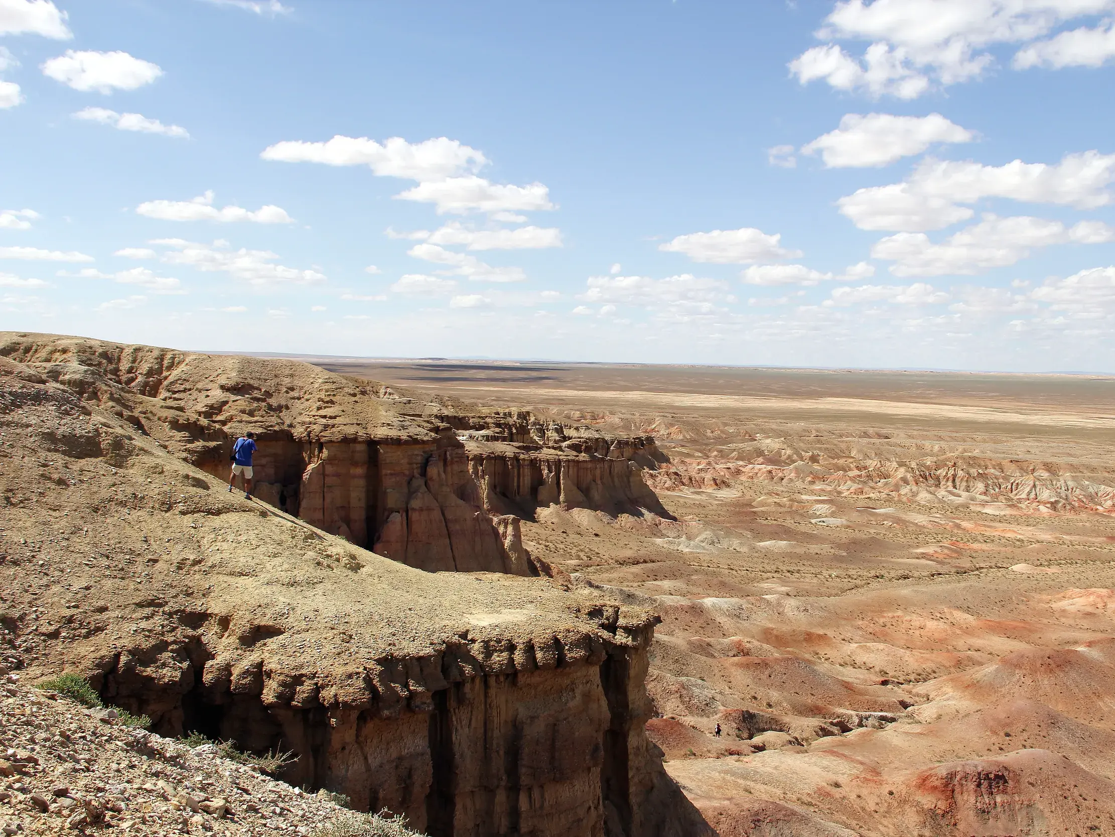 Wanderer mit Rucksack blickt von einer Klippe in den beeindruckenden Tsagaan Suvarga Canyon in der mongolischen Wüste Gobi.