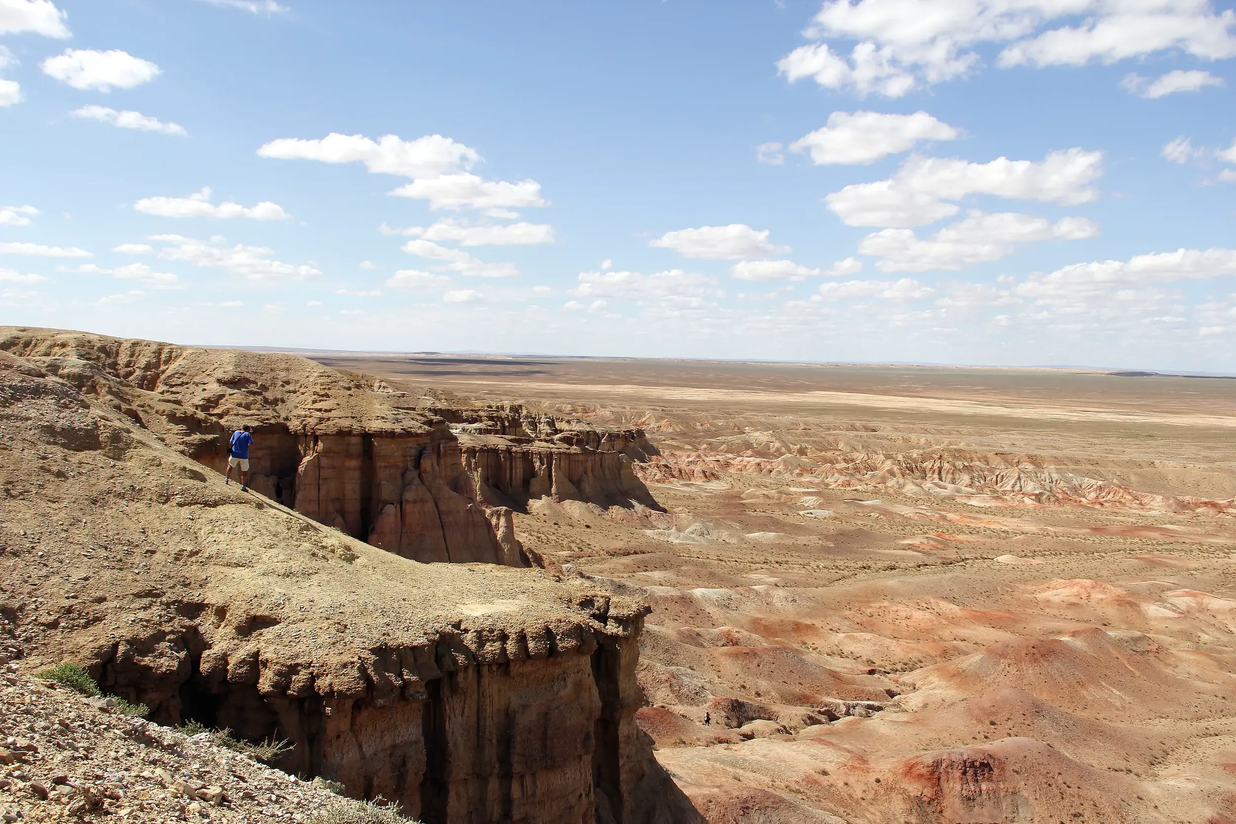 Wanderer mit Rucksack blickt von einer Klippe in den beeindruckenden Tsagaan Suvarga Canyon in der mongolischen Wüste Gobi.