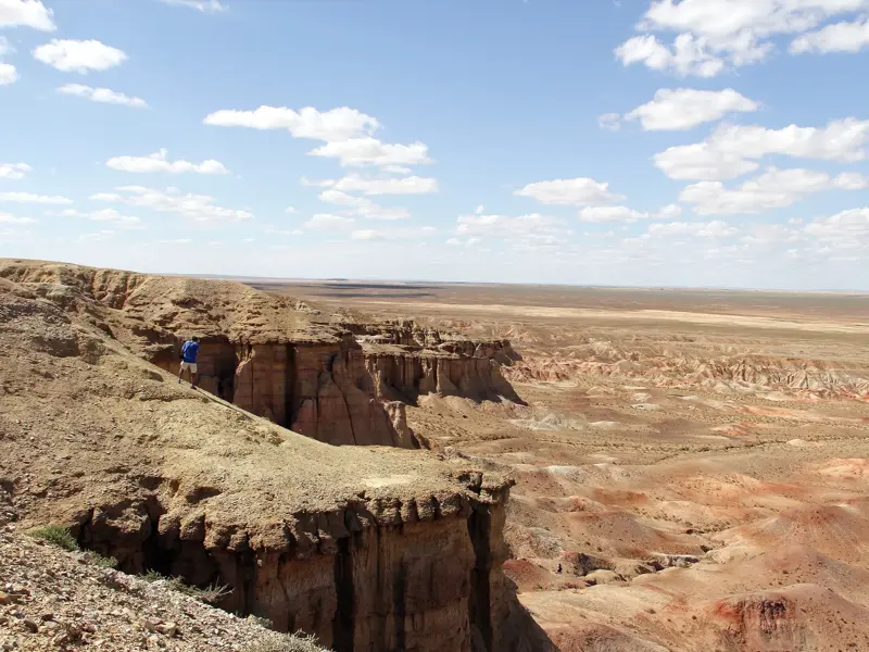 Wanderer mit Rucksack blickt von einer Klippe in den beeindruckenden Tsagaan Suvarga Canyon in der mongolischen Wüste Gobi.