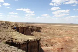 Wanderer mit Rucksack blickt von einer Klippe in den beeindruckenden Tsagaan Suvarga Canyon in der mongolischen Wüste Gobi.