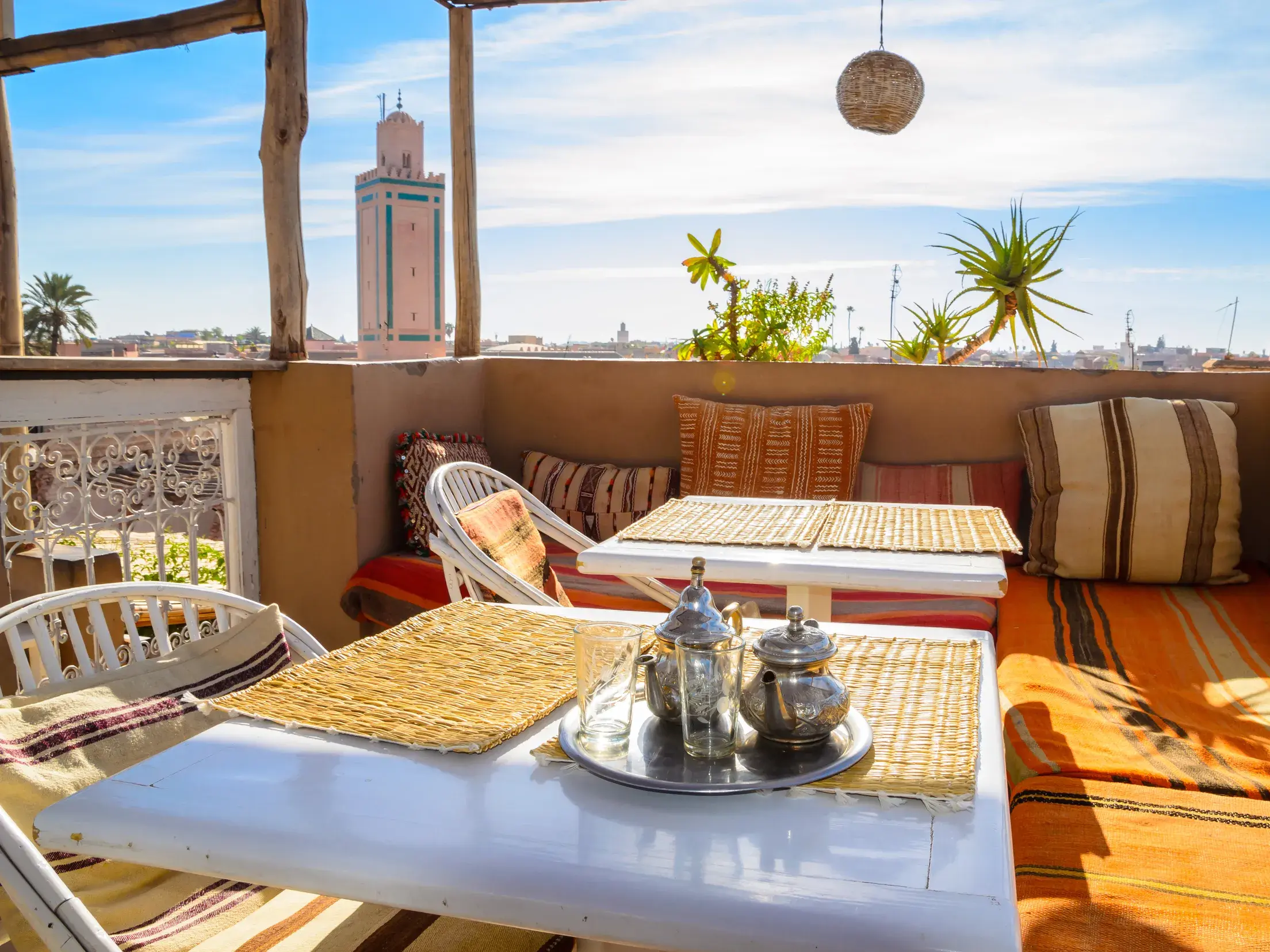 Gemütliche Riad-Dachterrasse mit marokkanischem Minztee und Blick über die Dächer von Marrakesch zur Koutoubia-Moschee.