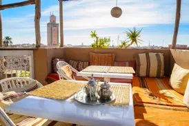 Gemütliche Riad-Dachterrasse mit marokkanischem Minztee und Blick über die Dächer von Marrakesch zur Koutoubia-Moschee.