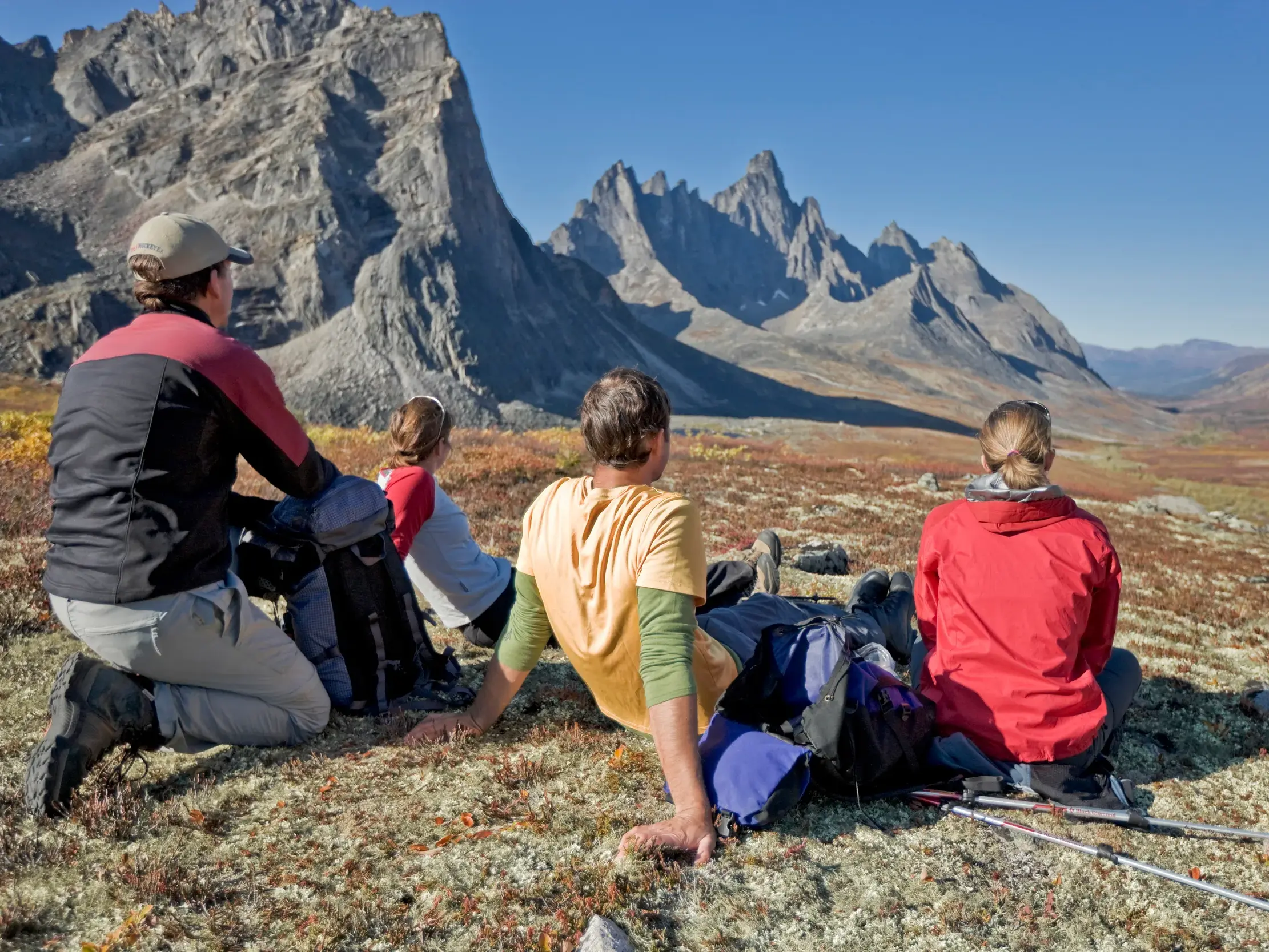 Wandergruppe bei einer Rast in der Tundra mit Blick auf die markanten Felsgipfel des Tombstone Territorial Park im Yukon.