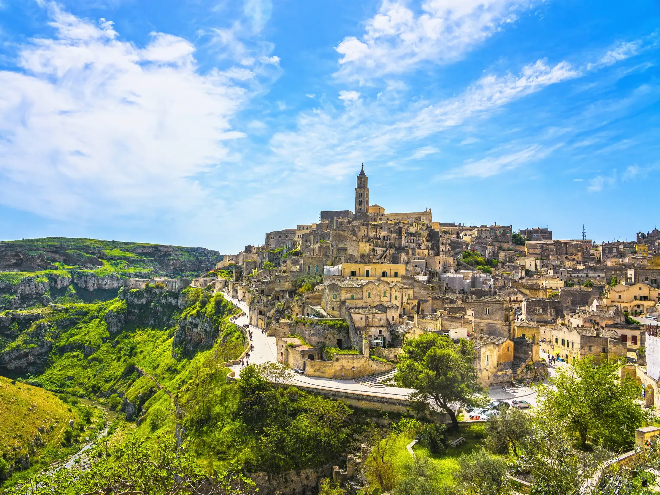 Panoramablick auf die historischen Sassi di Matera, UNESCO-Weltkulturerbe in der Basilikata, an einer grünen Schlucht.