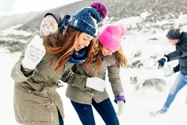 Junge Teilnehmer einer Gruppenreise haben eine ausgelassene Schneeballschlacht in der winterlichen Natur von Island.