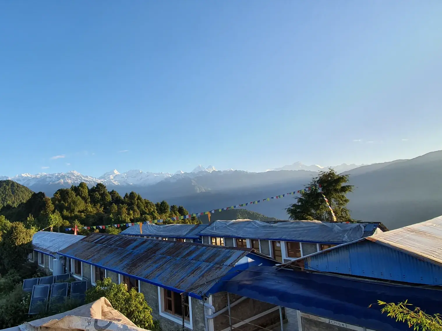Morgensonne über einer Lodge auf dem Helambu Climate Trek mit Panoramablick auf die Gipfel des Jugal Himal in Nepal.