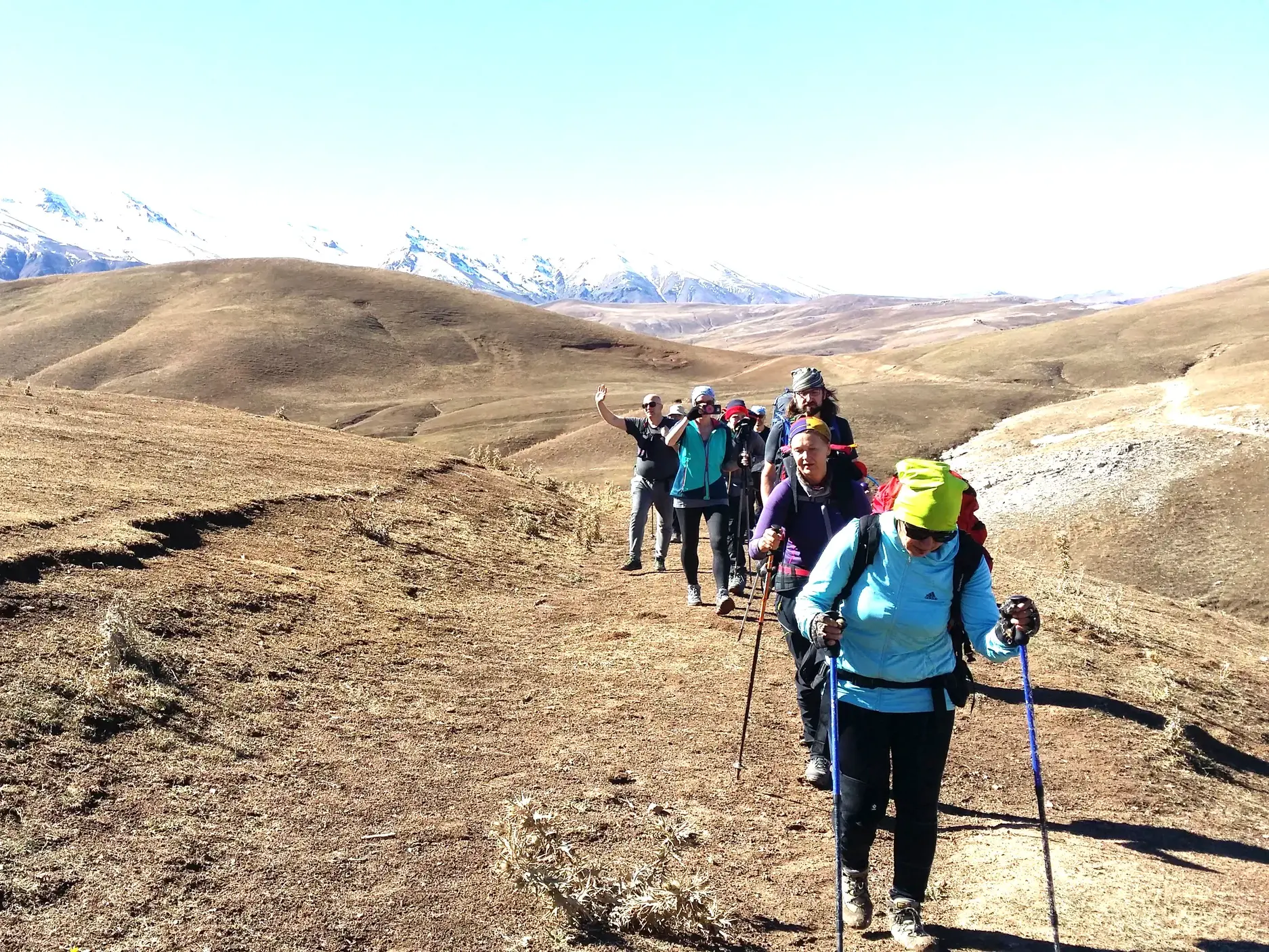 Hauser-Reisegruppe beim Trekking im Chimgan-Gebirge in Usbekistan mit Panoramablick auf die schneebedeckten Gipfel des Tienschan.