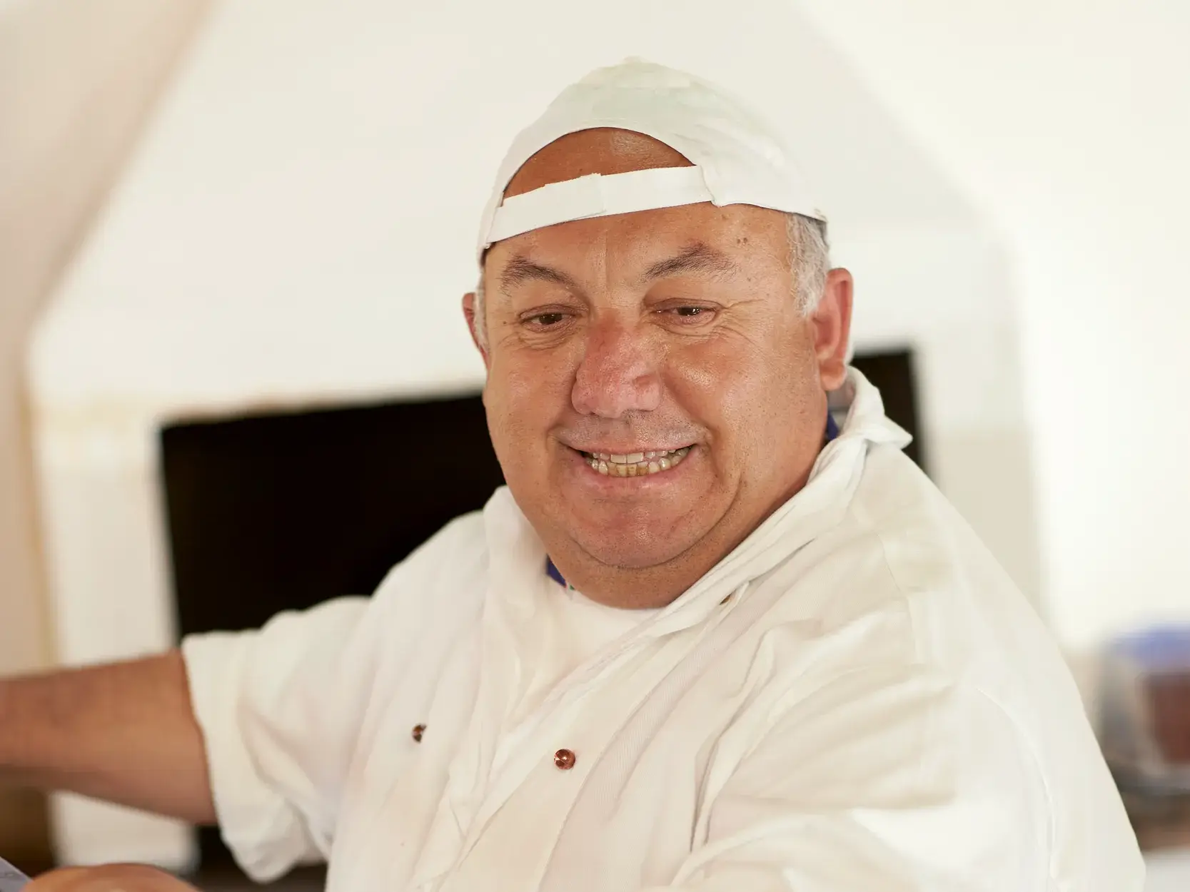 Ein lächelnder, älterer sizilianischer Mann schiebt frische Pizza in den Holzofen