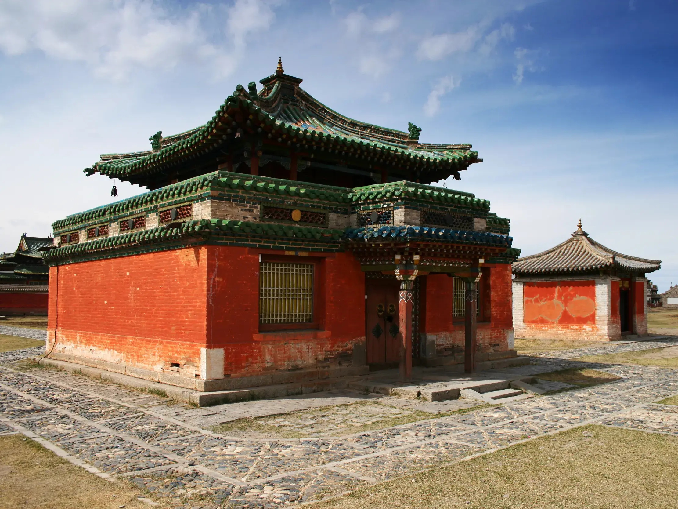 Historischer Tempel der Klosteranlage Erdene Zuu in Karakorum mit roten Mauern und geschwungenem grünen Pagodendach.