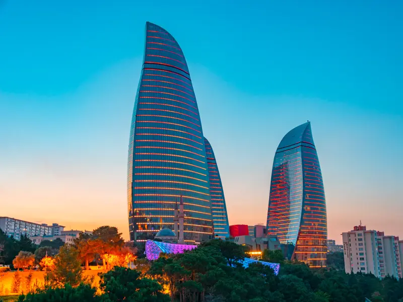 Die beleuchteten Flame Towers, das moderne Wahrzeichen von Baku, vor dem farbenprächtigen Himmel bei Sonnenuntergang.