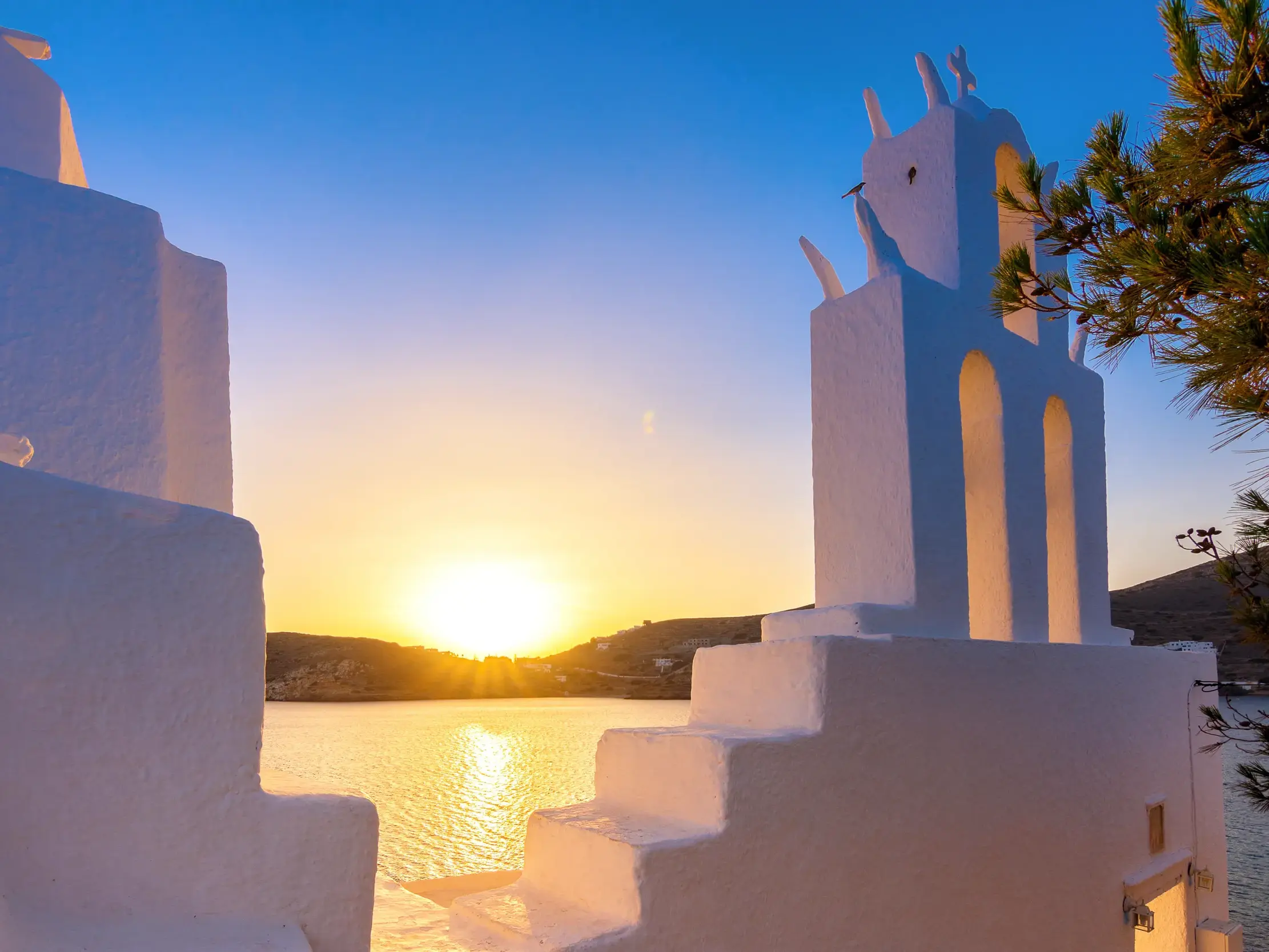Malerischer Sonnenuntergang über der Ägäis, gesehen von der weiß getünchten Kirche Panagia Gremiotissa auf Ios.