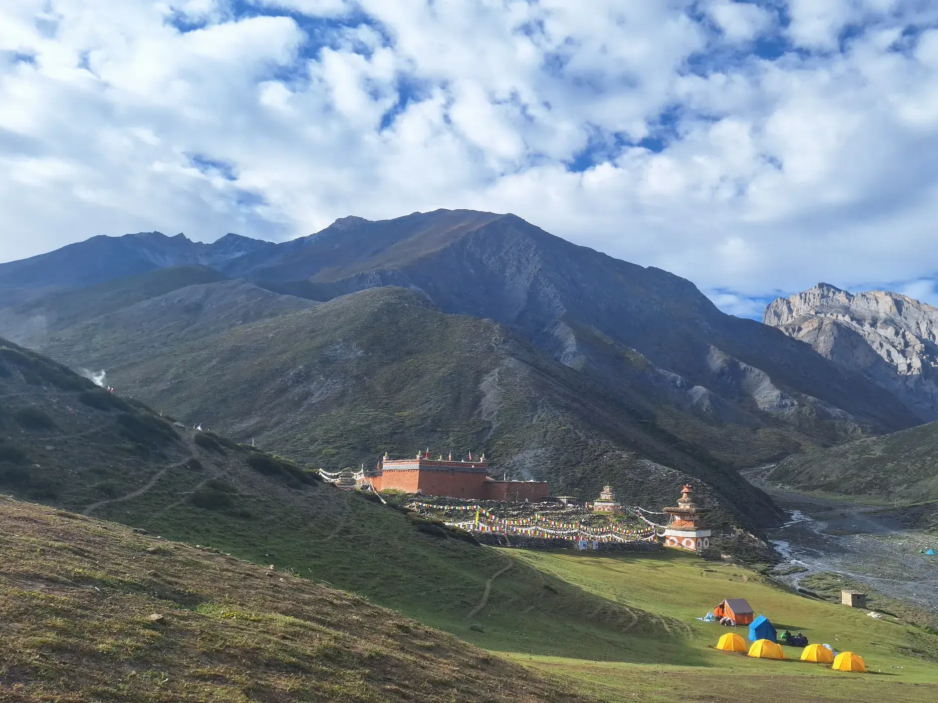 Gelbe Zelte eines Trekking-Camps auf einer Wiese vor dem Kloster Shey Gompa in der Bergwelt des Dolpo in Nepal.