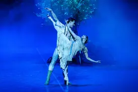 Balletttänzer bei einer anmutigen Hebefigur auf blau beleuchteter Bühne in der Hamburgischen Staatsoper.