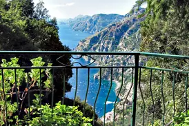 Panoramablick von einem Wanderweg auf die steile Amalfiküste mit dem Fjord von Furore und zahlreichen Booten im blauen Meer.
