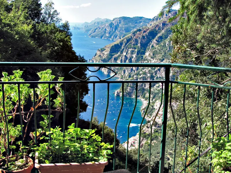 Panoramablick von einem Wanderweg auf die steile Amalfiküste mit dem Fjord von Furore und zahlreichen Booten im blauen Meer.