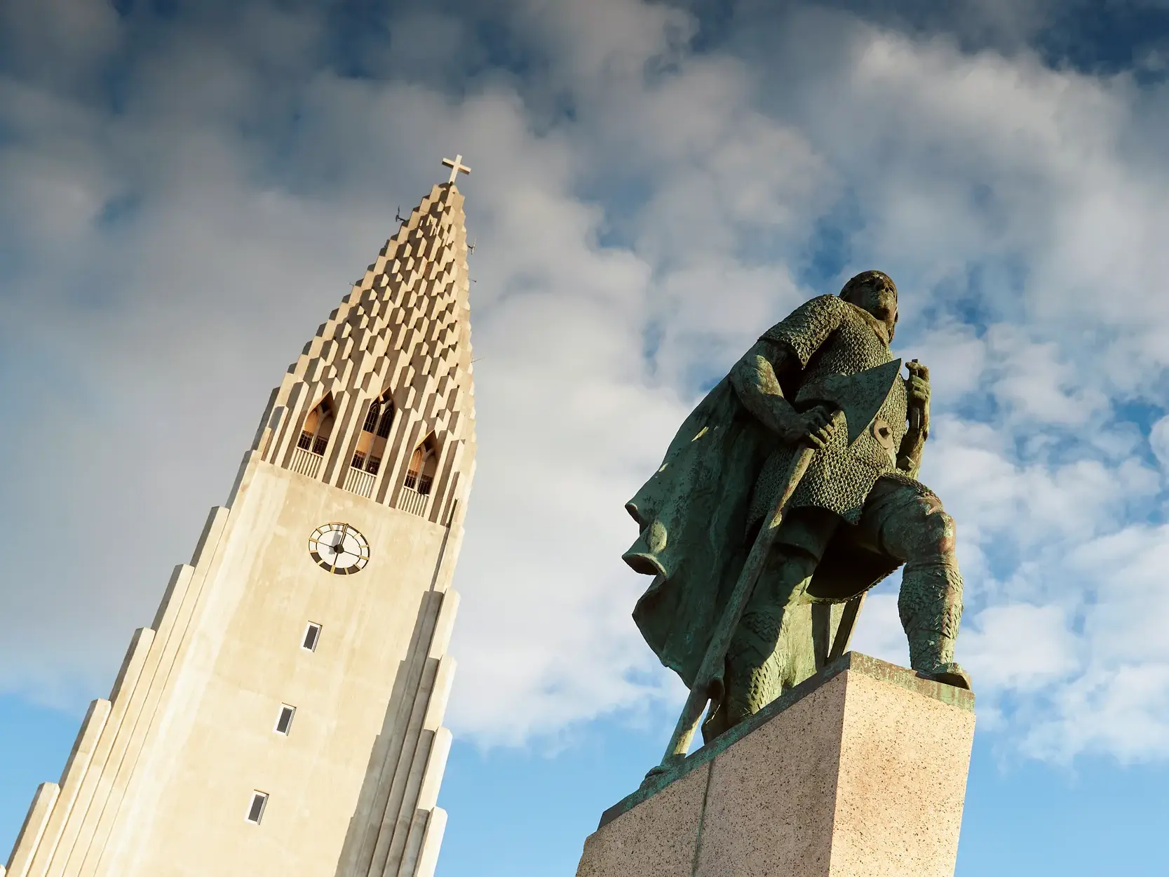 Statue des Entdeckers Leif Erikson vor der imposanten Hallgrímskirkja, dem Wahrzeichen von Reykjavik, bei blauem Himmel.