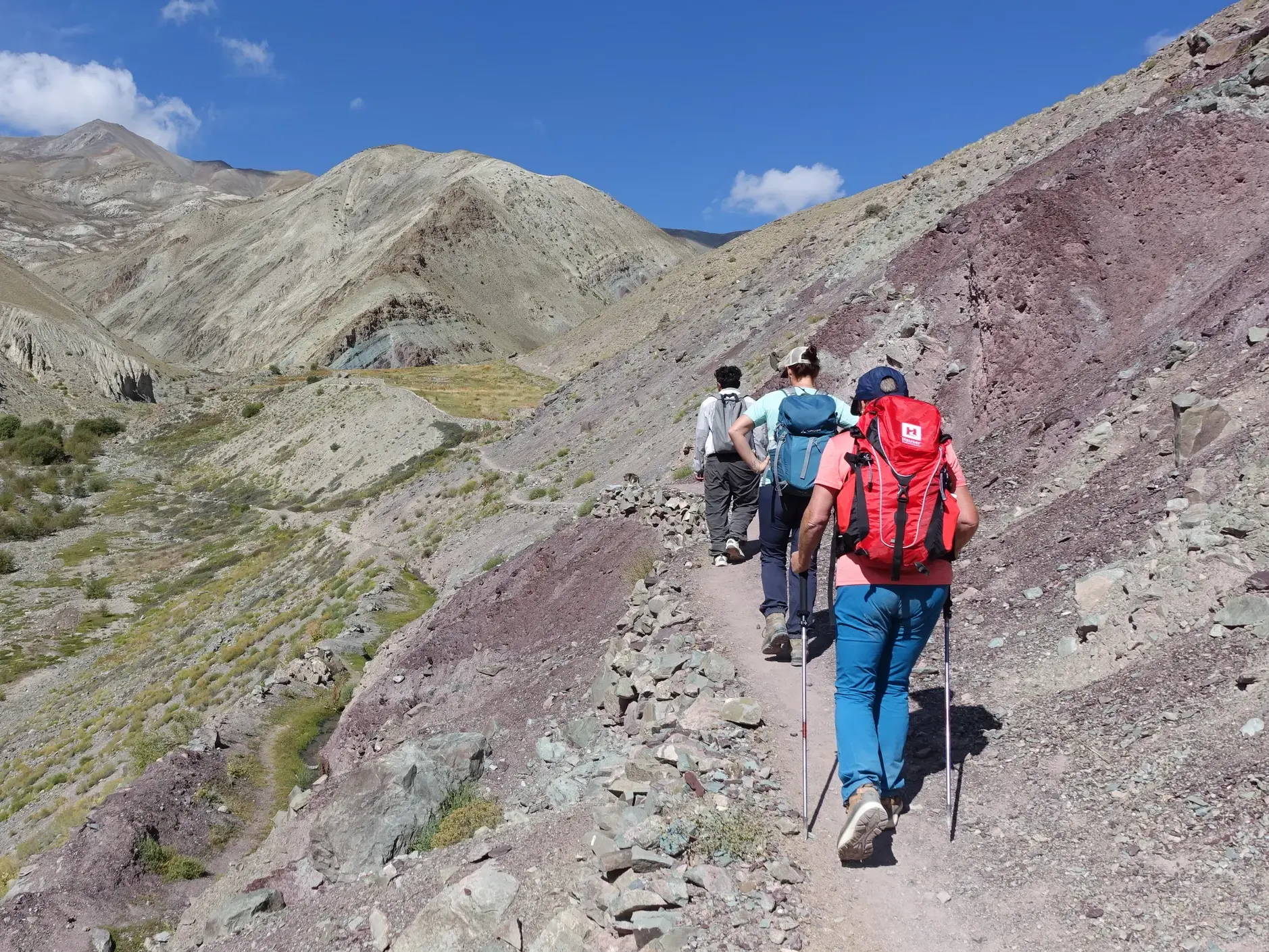 Reisegruppe beim Trekking auf einem schmalen Pfad zum Ganda La Base Camp mit Blick auf die bunte Berglandschaft Ladakhs.