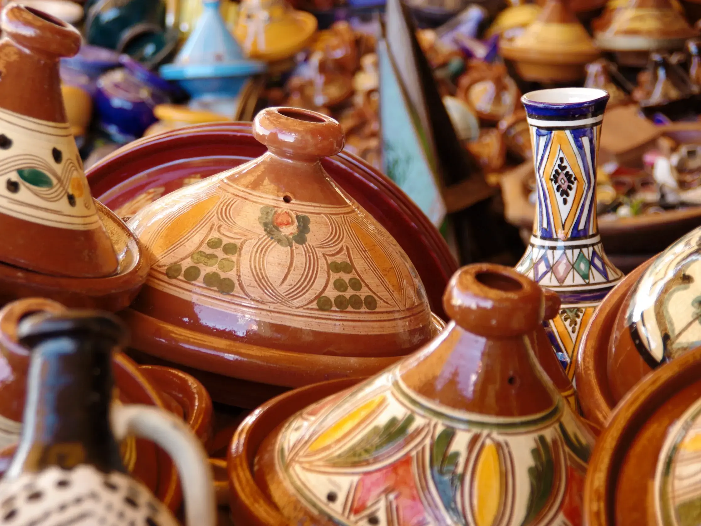 Farbenfrohe, kunstvoll bemalte Tajinen aus Ton stehen dicht an dicht auf einem Marktstand in den lebhaften Souks von Marrakesch.