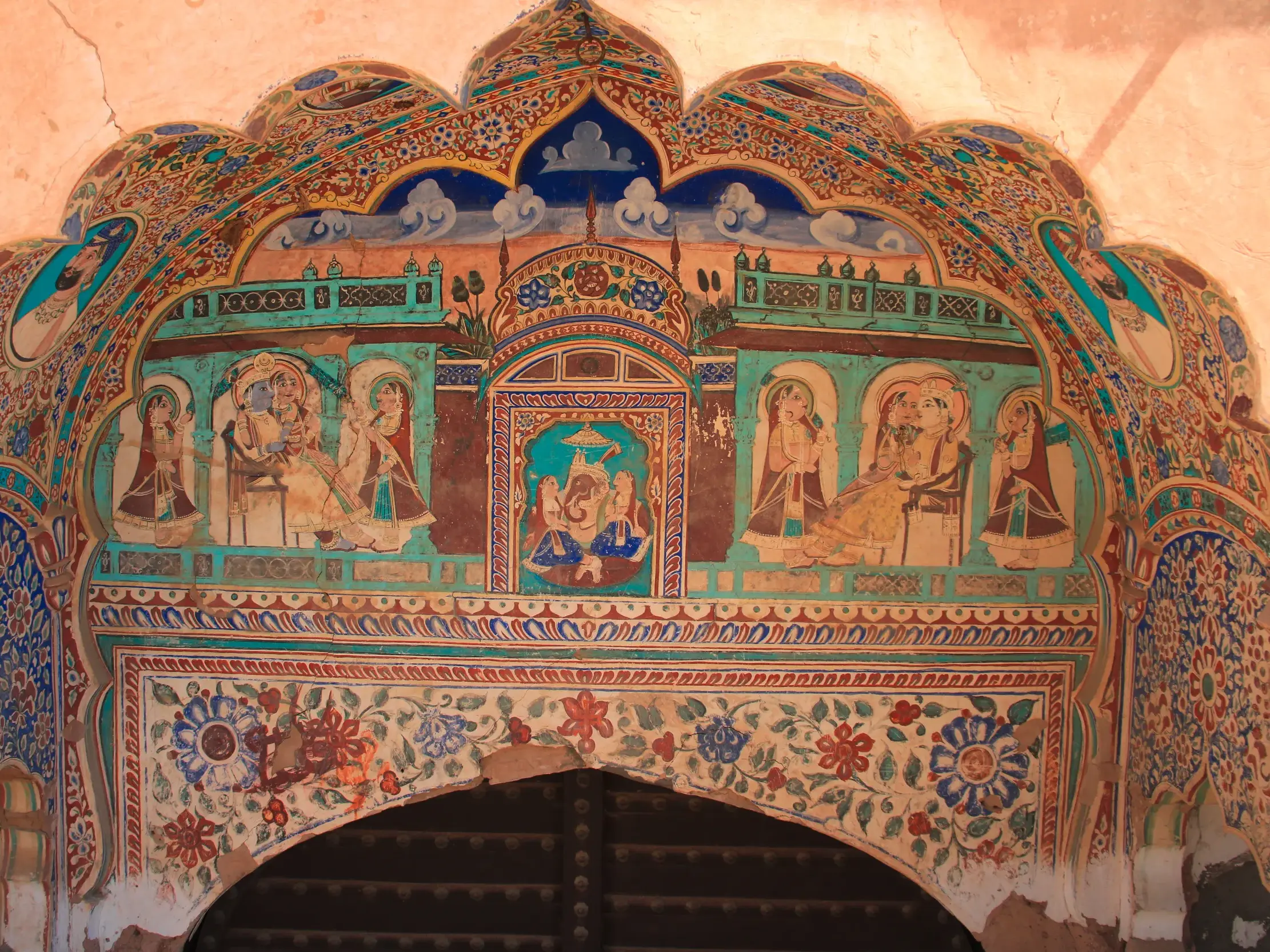 Farbenprächtige Malereien mit Figurenszenen über dem Torbogen eines reich verzierten Havelis (Händlerhaus) in Rajasthan.