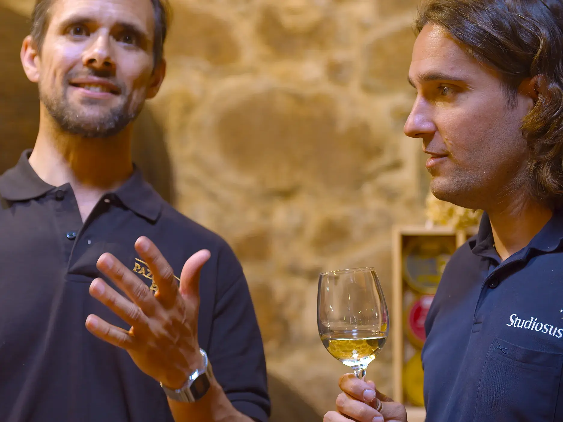 Ein lokaler Winzer erklärt einem Studiosus-Reisenden bei einer Weinprobe in einem Weinkeller in Galicien einen Weißwein.