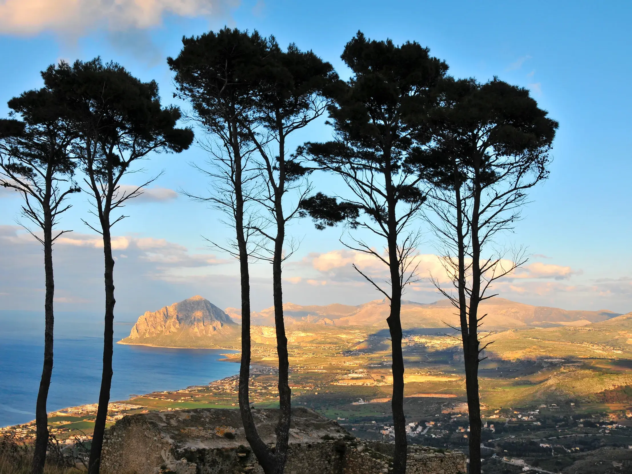 Abendlicher Weitblick von Erice durch Pinien auf den Monte Cofano und die Küstenlandschaft bei Trapani auf Sizilien.