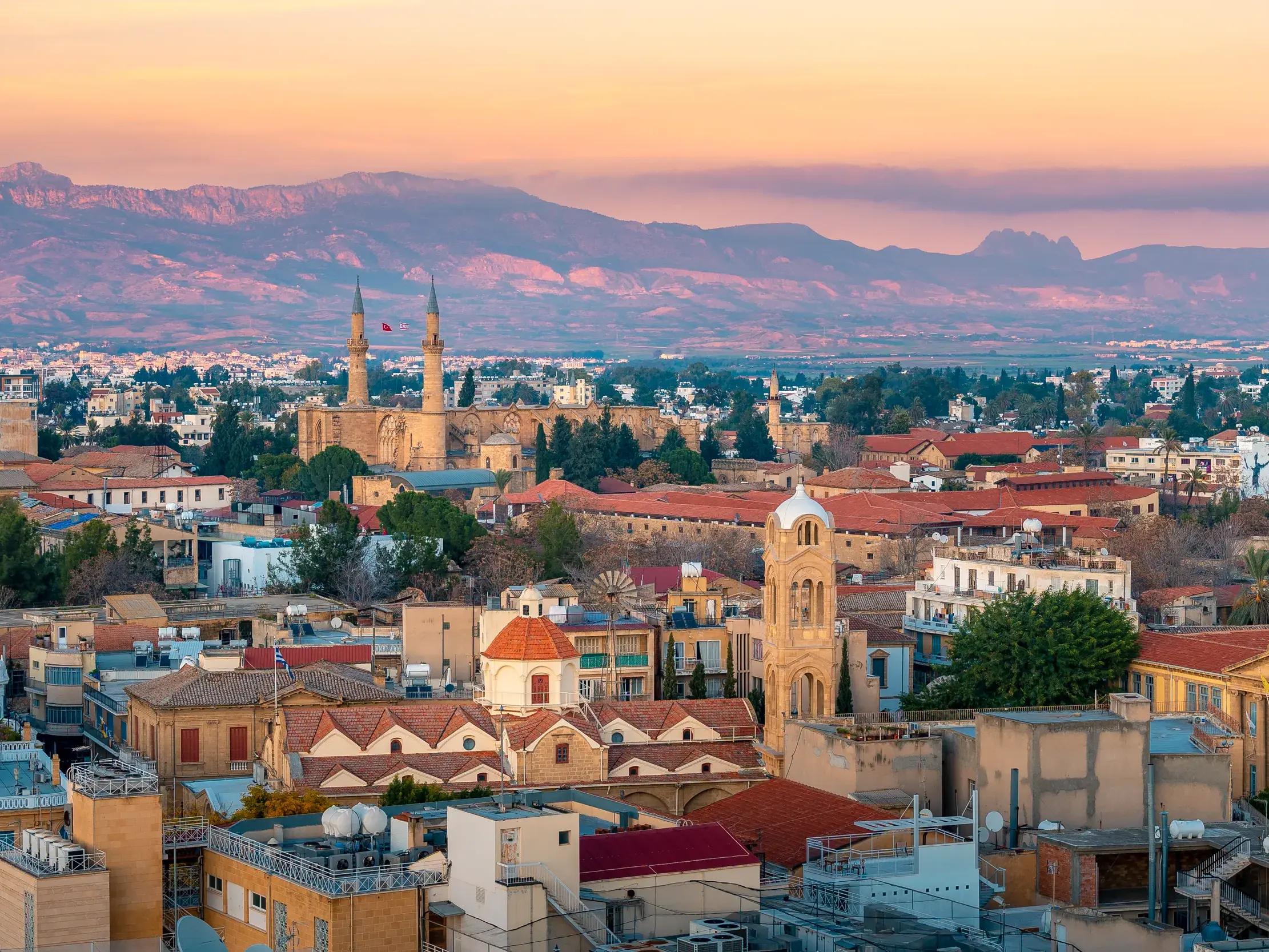 Panoramablick über die Dächer der geteilten Hauptstadt Nikosia auf Zypern mit der Selimiye-Moschee bei Sonnenuntergang.