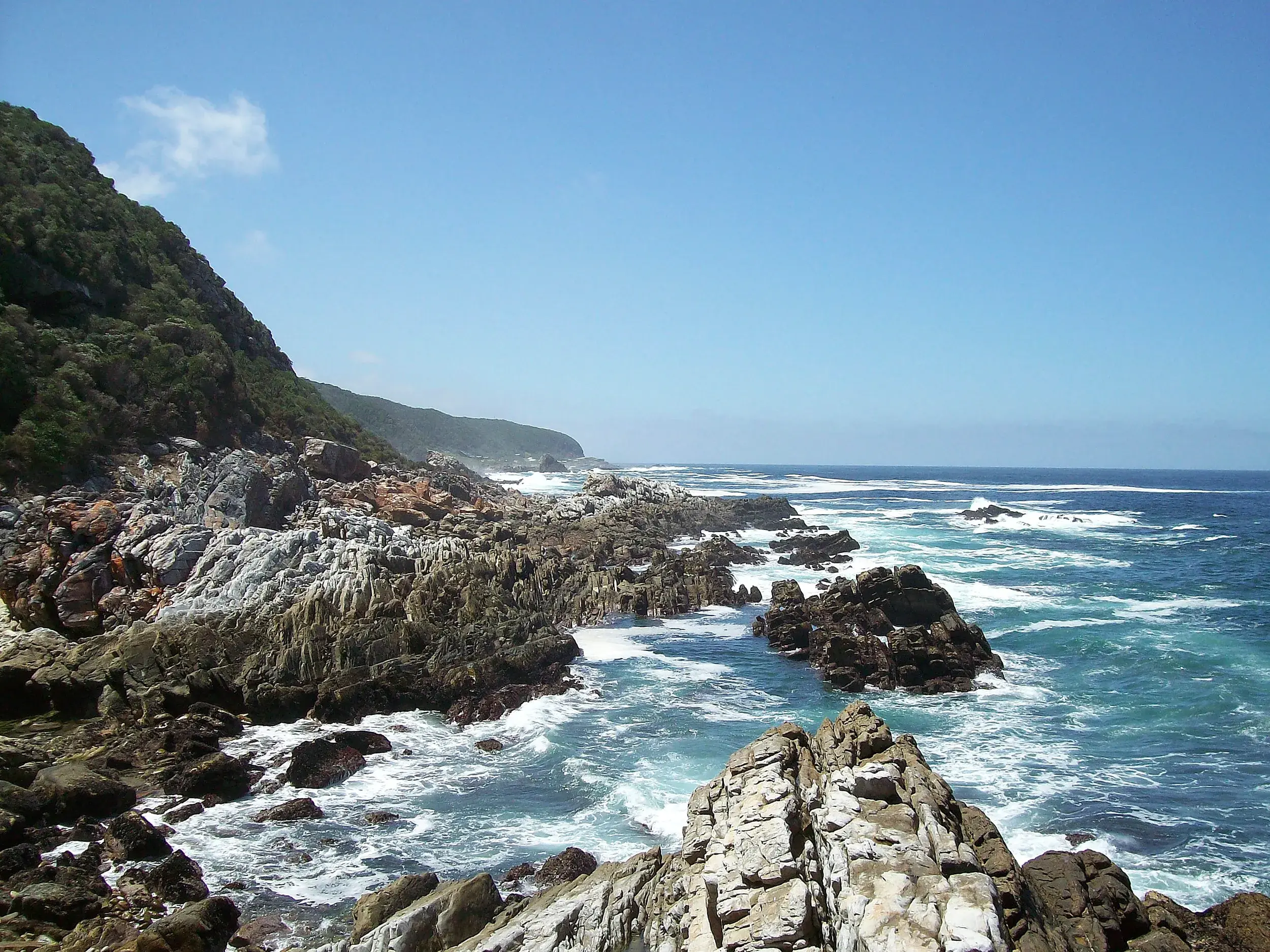 Wellen brechen an der zerklüfteten Felsküste des Tsitsikamma Nationalparks auf dem berühmten Otter Trail in Südafrika.