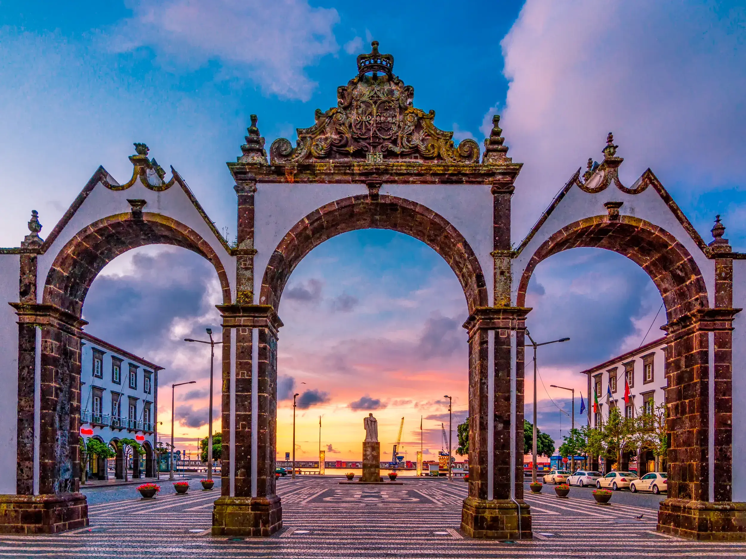 Die historischen Stadttore Portas da Cidade in Ponta Delgada auf dem schwarz-weiß gemusterten Platz bei Sonnenuntergang.