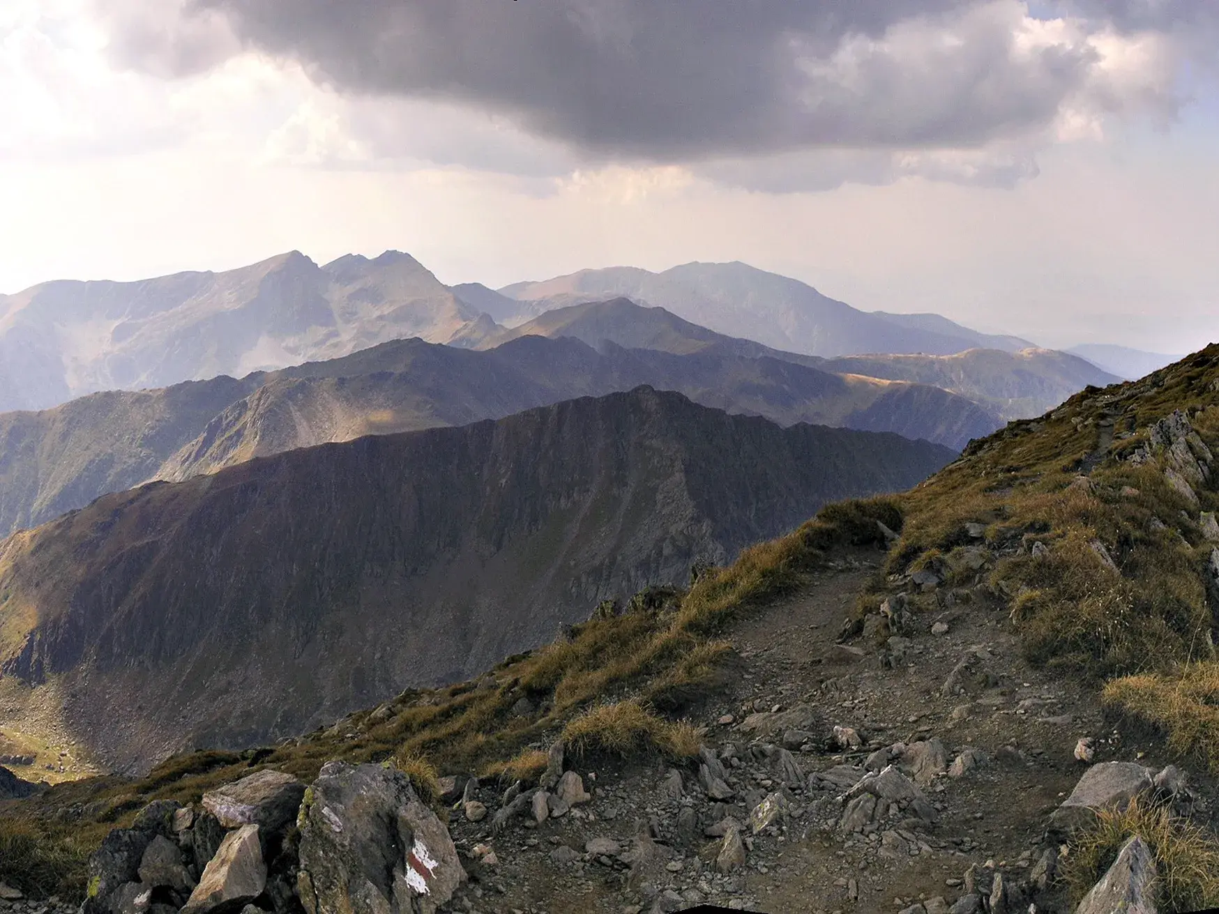 Panoramablick beim Trekking auf einem steinigen Höhenweg im Fagaras Gebirge mit Sicht auf die Gipfel der Südkarpaten.
