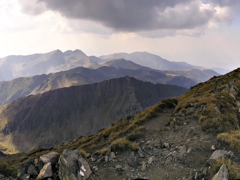 Panoramablick beim Trekking auf einem steinigen Höhenweg im Fagaras Gebirge mit Sicht auf die Gipfel der Südkarpaten.