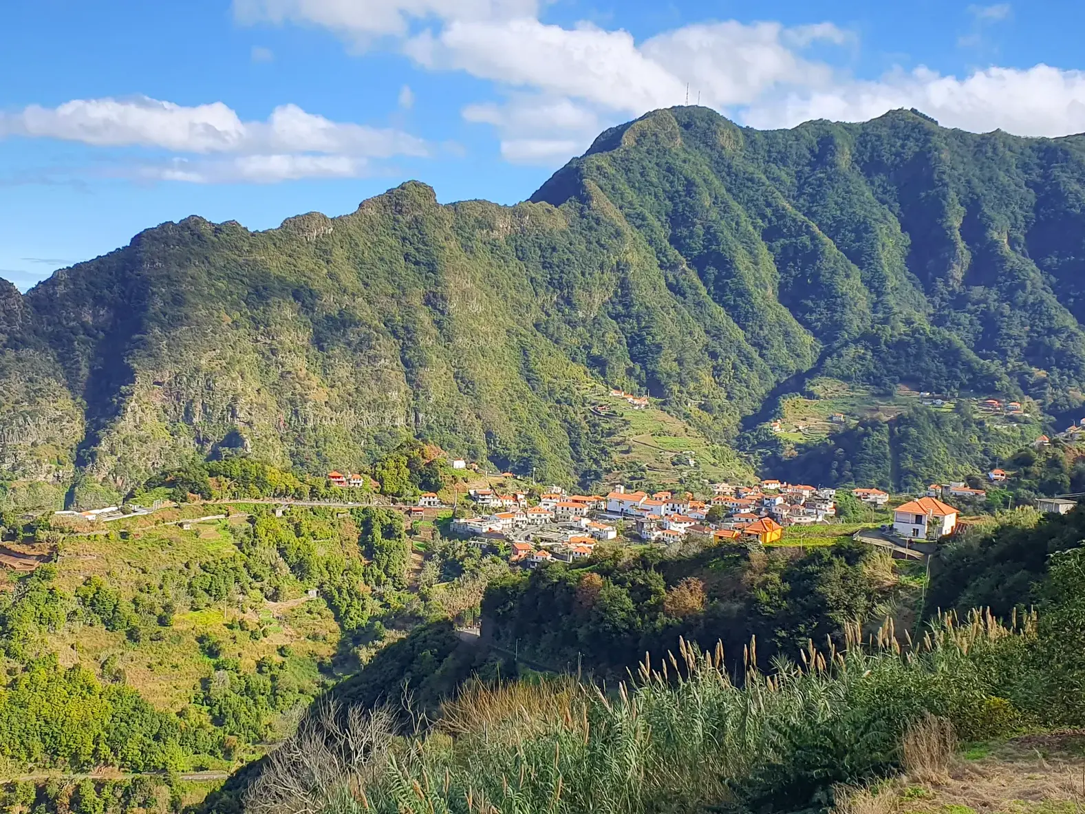 Aussicht beim Wandern auf das Küstendorf São Vicente, eingebettet in die grüne Bergwelt Madeiras mit Blick auf den Atlantik.