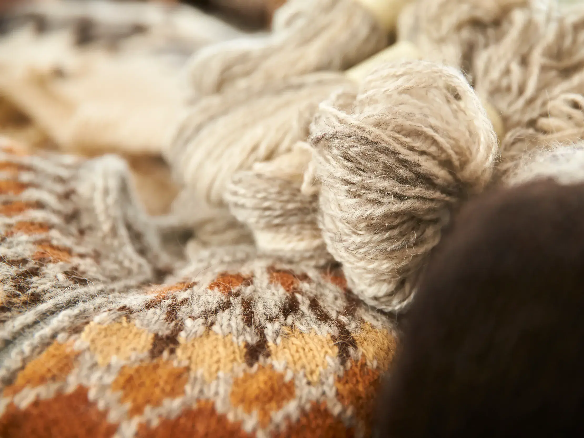 Nahaufnahme von traditioneller Islandwolle und einem Islandpullover mit typischem Strickmuster in einer Wollmanufaktur in Island.