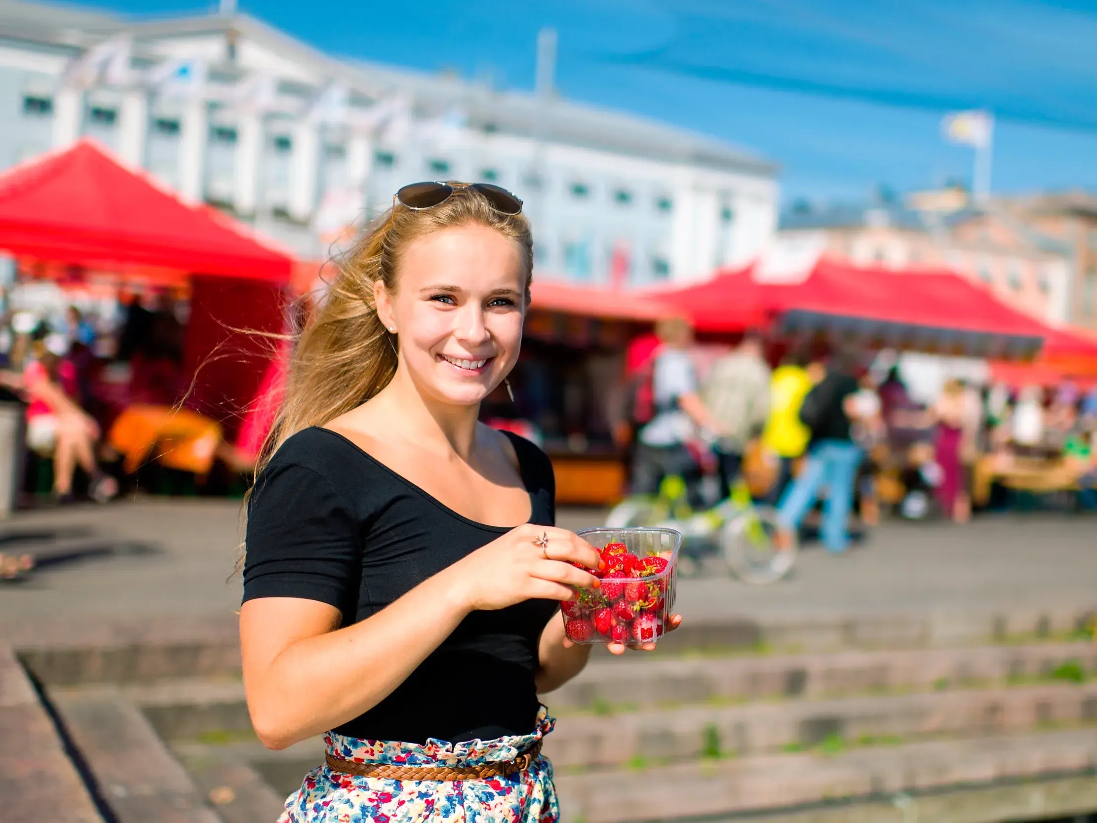 Eine Teilnehmerin einer Studiosus-Studienreise genießt frische Beeren auf dem sonnigen Marktplatz am Hafen von Helsinki.