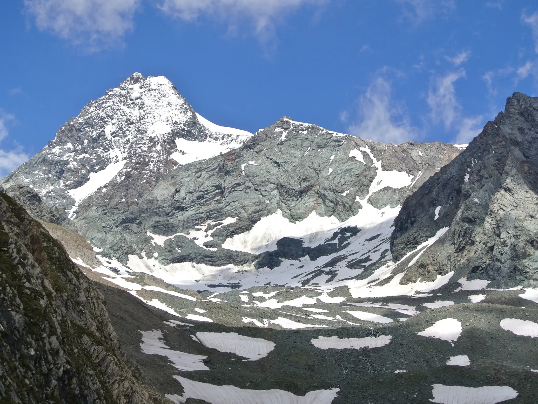 Der schneebedeckte Gipfel des Großglockners in der hochalpinen Felslandschaft des Nationalparks Hohe Tauern an einem Sonnentag.