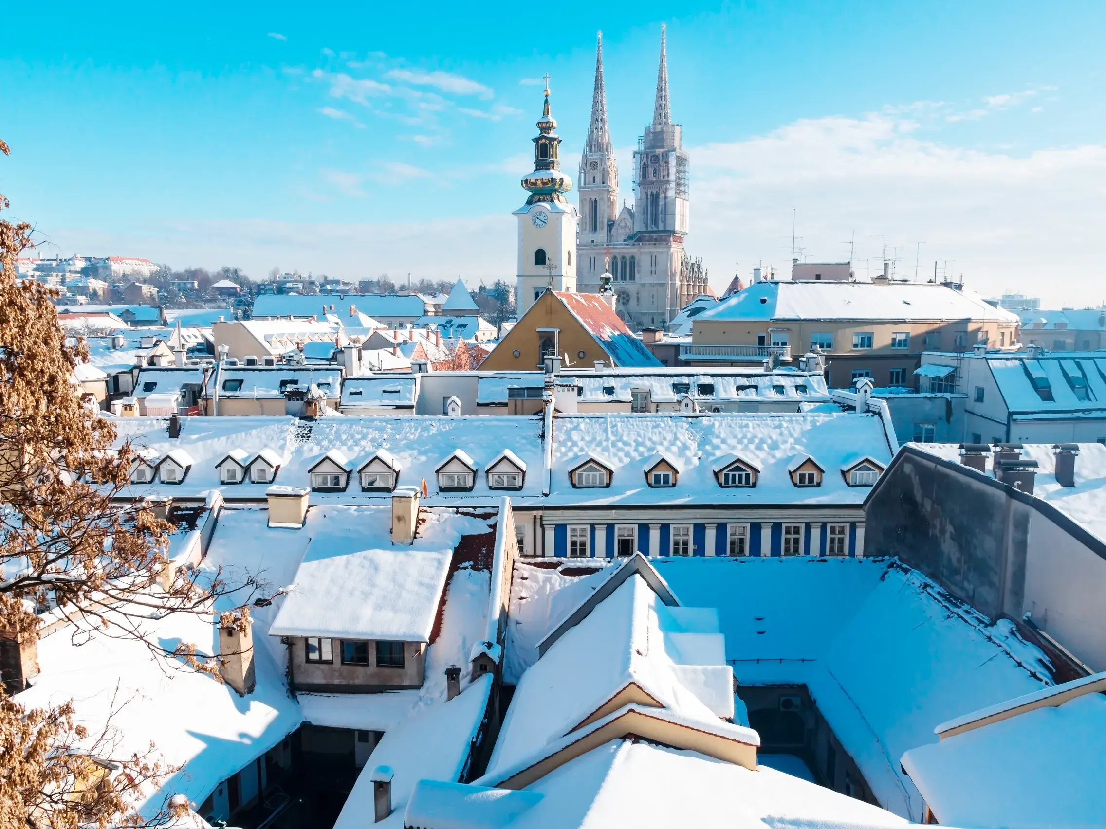 Verschneite Dächer der Altstadt von Zagreb an einem sonnigen Wintertag mit der neugotischen Kathedrale im Hintergrund.